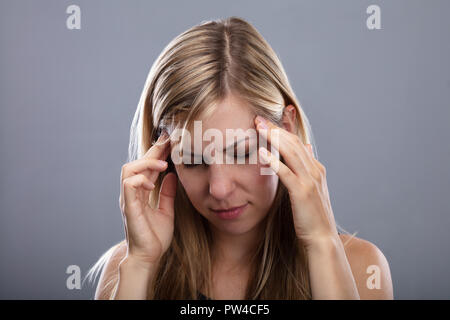 Foto O blonde junge Frau leidet unter Kopfschmerzen. Stockfoto