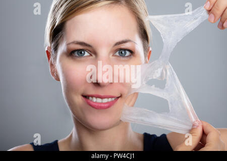 Nahaufnahme einer lächelnde Frau Peeling aus einer Gesichtsmaske Stockfoto