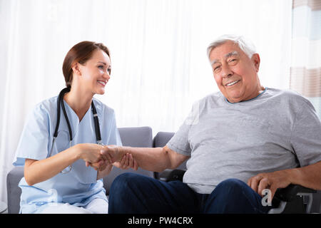 Porträt eines lächelnden älteren Mann sitzt im Rollstuhl mit weiblichen Krankenschwester Stockfoto