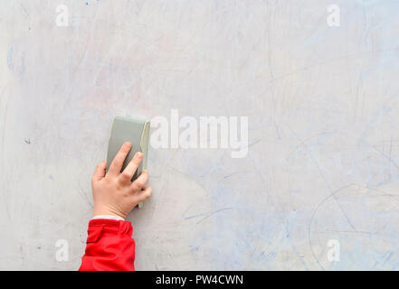 Schülerin hand Löscht auf Tafel mit board Radiergummi in Klassenzimmer, Bildung Konzept. Stockfoto