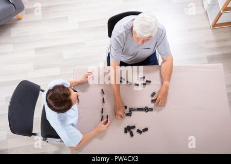 Ansicht der weiblichen Wärter und älterer Mann spielt Domino Stockfoto