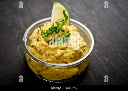 Schüssel mit frische und köstliche und grüne Guacamole auf einem alten schwarzen Holztisch in einem Pub Stockfoto
