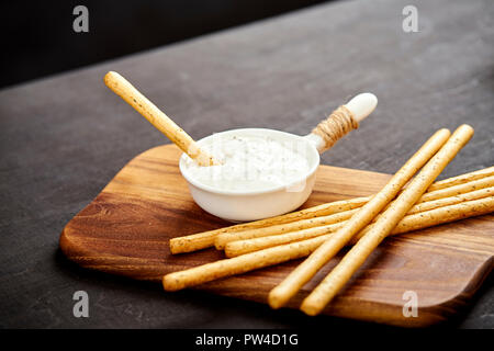 Leckere salzige Sticks und Knoblauch dip auf einem alten schwarzen Holztisch in einem Pub Stockfoto