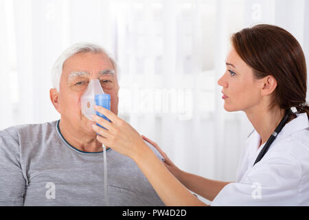 Junge Ärztin Holding Sauerstoff Maske über von männlichen Patienten Gesicht Stockfoto