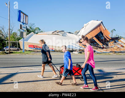 Danielle Kaufmann zieht einen Wagen als sie und ihre Kinder vorbei beschädigte Gebäude in Panama City, Florida nach dem Hurrikan Michael. Stockfoto