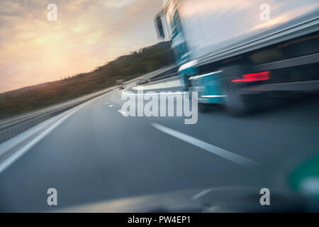 Verschwommene Bewegung der Stapler fährt auf der Straße durch Auto Windschutzscheibe bei Sonnenuntergang gesehen Stockfoto