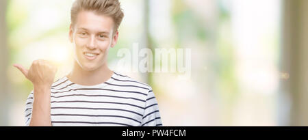 Jungen gutaussehenden blonden Mann Streifen tragen SAILOR T-Shirt zeigt mit Finger- und oben mit glücklichen Gesicht lächelnd Stockfoto