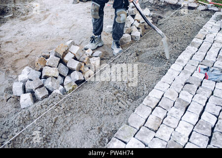 Bauarbeiter Inverkehrbringen Stein Fliesen für Gehweg, Terrasse. Arbeitnehmer Inverkehrbringen Granit Kopfsteinpflaster auf der Terrasse Stockfoto