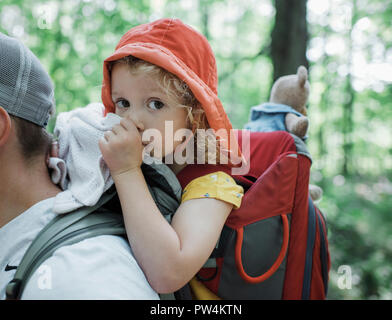 Portrait von niedlichen Tochter Daumenlutschen, während der Vater im Wald durchgeführt werden Stockfoto