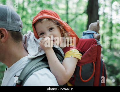 Portrait von niedlichen glückliche Tochter Daumenlutschen, während der Vater im Wald durchgeführt werden Stockfoto