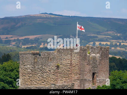 St George's Flagge vom Großen Turm von Ludlow Castle, Shropshire, mit braunen Clee im Hintergrund zu sehen. Stockfoto