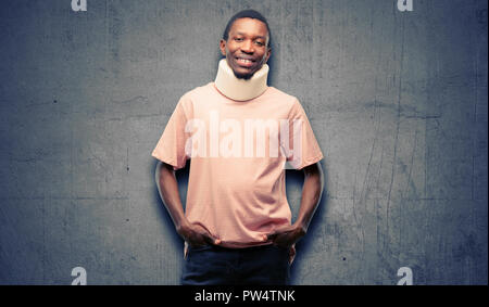 Verletzte afrikanischen schwarzen Mann, der Hals mit einem großen natürlichen Lächeln brace zuversichtlich und fröhlich lachend Stockfoto