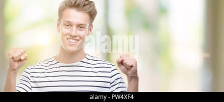 Jungen gutaussehenden blonden Mann Streifen tragen Sailor t-shirt Schreien stolz und feiern Sieg und Erfolg sehr aufgeregt, jubelnde Emotion Stockfoto