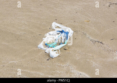 Single use Kunststoff Warenkorb gewaschen, am Strand und im Sand vergraben, ein Beispiel für den Müll in den Ozeanen rund um die Welt Stockfoto