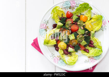 Dreifarbige Salat mit Bohnen, Tomaten, Kohl und Avocado auf einem Bett von Juwel Kopfsalat. Stockfoto