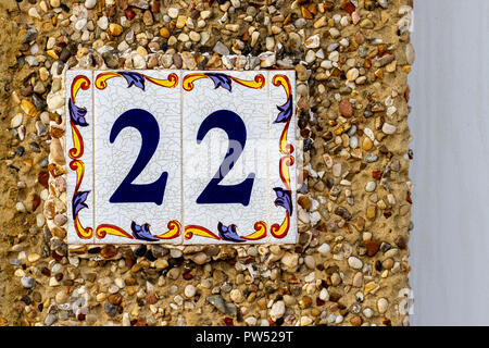 Haus Nummer 22 mit den zweiundzwanzig in Blau auf bunten Fliesen oder Azulejos in einem strukturierten Pflasterwand außerhalb Stockfoto
