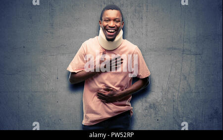 Verletzte afrikanischen schwarzen Mann, der Hals mit einem großen natürlichen Lächeln brace zuversichtlich und fröhlich lachend Stockfoto