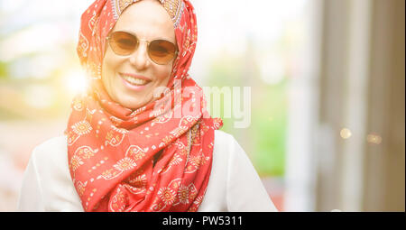 Mittleres Alter muslimisch-arabischen Frau, tragen, Hijab überzeugt und zufrieden mit einen großen natürlichen Lächeln Lachen Stockfoto