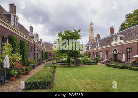 Das armenhaus der grünen Garten im alten Zentrum von Haarlem mit dem Turm der Grote Kerk oder St. Bavokerk im Hintergrund Stockfoto