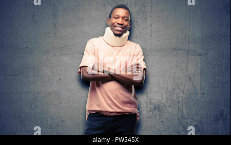 Verletzte afrikanischen schwarzen Mann, Neck Brace mit verschränkten Armen zuversichtlich und zufrieden mit einen großen natürlichen Lächeln Lachen Stockfoto