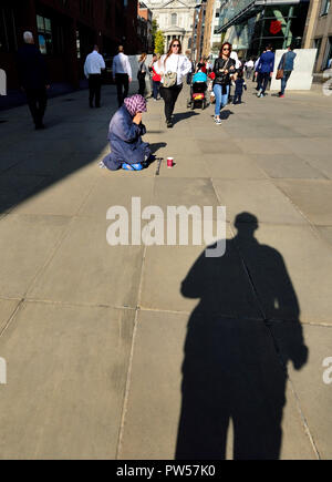 Frau in Peter's Hill betteln, zwischen der Millennium Bridge und St Paul's Cathedral, London, England, UK. Stockfoto