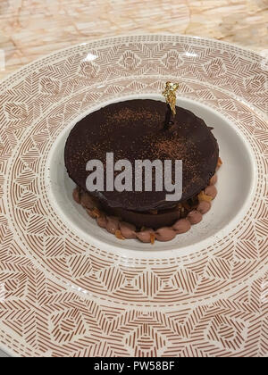 Kleine Schokolade Kuchen auf einem großen Teller mit einem gold Dekor auf der Oberseite. Stockfoto