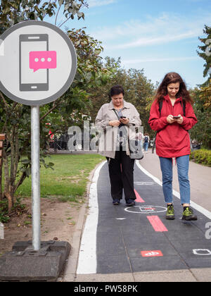 VILNIUS, LITAUEN - 14. SEPTEMBER 2018: Frauen gehen auf dedizierte mobile phone Lane in Vokieciu Straße Stockfoto