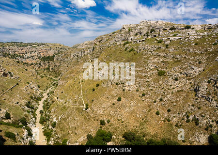 Panorama der Hügel vor Matera mit Höhlen in den Felsen und dem Bach am unteren Ende der Schlucht geschnitzt Stockfoto