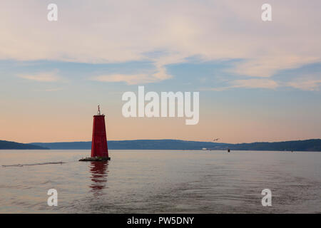 Eine grosse rote Boje markiert den Eingang des Cayuga Einlass aus Cayuga Lake, in Ithaca, New York, in der Finger Lakes Region während einer ruhigen Sonnenuntergang. Stockfoto