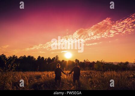 Romantische glückliches Paar beobachten Sonnenuntergang in der Natur Stockfoto