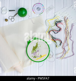 Embroidery hoop with blank fabric, colored sewing threads and various sewing buttons. View from above. Stockfoto