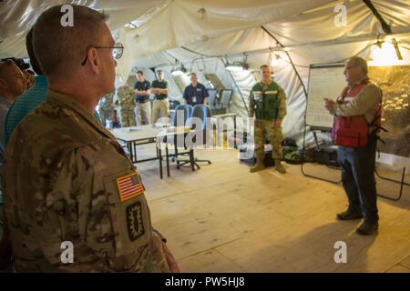 Us-Armee Oberst Marty Muchow hört kurz vor einem Nationalen Technischen nuklearen Forensik (NTNF) Mission, bei Prominenten Jagd auf Onate National Guard Complex, New York, Sept. 20, 2017. Die Prominente Jagd Übung bringt in Bundes-, Landes- und lokalen Agenturen zu den 20 chemischen, biologischen, nuklearen Sprengstoff (CBRNE) Befehl zu bestätigen als Teil der NTNF Boden Sammlung Task Force (GCTF). Stockfoto