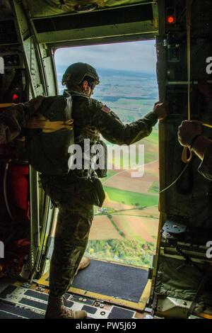 Ein jumpmaster auf das erste Bataillon zugeordnet, 10 Special Forces Group (Airborne), blickt die Tür einer C-130 Hercules für einen Referenzpunkt bei einem Betrieb in der Nähe von Stuttgart, Deutschland, Sept. 20, 2017. Jumpmasters Sie Referenzpunkte verwenden, um sicherzustellen, dass Sie über die richtige Flugbahn und zu helfen, den Abstand zu ihren Drop Zone bestimmen. Der Sprung verdeutlichten die Fähigkeit Gruppe luftgestützten Hilfsaktionen in der Europäischen Theater zu führen. Airborne Einfügungen sind eine der vielen infiltration Plattformen Spezielle Operationen zur Verfügung, wenn die Reaktion auf eine Krise. Stockfoto