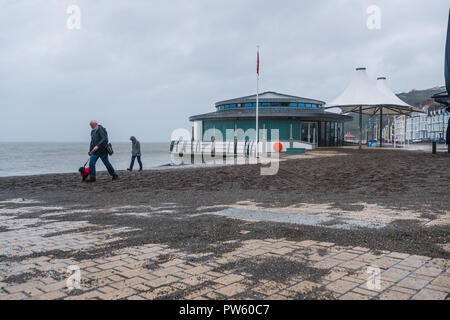 Aberystwyth, Wales, UK. 13. Oktober, 2018. UK Wetter: Nach einer Nacht, der starken Winde und Gezeiten im Zusammenhang mit dem Sturm Callum, der Promenade in Aberystwyth ist in Hunderte von Tonnen von Sand und Kies bedeckt. Mit einer weiteren Flut an diesem Morgen, und die Winde wieder über 50 mph wehenden, weitere Schäden zu rechnen ist. Foto: Keith Morris/Alamy leben Nachrichten Stockfoto
