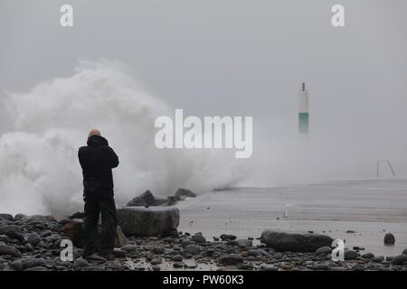 Aberystwyth, Wales, UK. 13. Oktober, 2018. Aberystwyth, Ceredigion, Wales, Großbritannien, 13. Oktober 2018 Großbritannien Wetter: Starke Winde und Wellen des Meeres Abwehr Hit in Aberystwyth als Mitglied der Öffentlichkeit aus der Nähe erhält. Credit: Ian Jones/Alamy Live News Credit: Ian Jones/Alamy leben Nachrichten Stockfoto