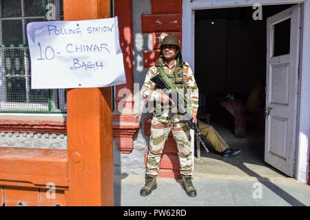 Srinagar, Kashmir. 13. Oktober 2018. Eine paramilitärische Trooper steht Warnung vor dem Wahllokal in der dritten Phase der Kommunalwahlen in SrinagarKashmir. Die dritte Phase des Jammu und Kaschmir städtischen lokalen Körper begann in 300 Wahllokalen bei 6 am Samstag unter strengen Sicherheitsmaßnahmen bin. Mehr als 365 Kandidaten sind in den Kampf für die Wahlen. Credit: SOPA Images Limited/Alamy leben Nachrichten Stockfoto