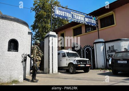 Srinagar, Kashmir. 13. Oktober 2018. Eine paramilitärische Trooper steht Warnung vor dem Wahllokal in der dritten Phase der Kommunalwahlen in SrinagarKashmir. Die dritte Phase des Jammu und Kaschmir städtischen lokalen Körper begann in 300 Wahllokalen bei 6 am Samstag unter strengen Sicherheitsmaßnahmen bin. Mehr als 365 Kandidaten sind in den Kampf für die Wahlen. Credit: SOPA Images Limited/Alamy leben Nachrichten Stockfoto