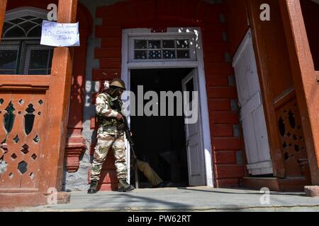 Srinagar, Kashmir. 13. Oktober 2018. Eine paramilitärische Trooper hält Mahnwache vor dem Wahllokal in der dritten Phase der Kommunalwahlen in SrinagarKashmir. Die dritte Phase des Jammu und Kaschmir städtischen lokalen Körper begann in 300 Wahllokalen bei 6 am Samstag unter strengen Sicherheitsmaßnahmen bin. Mehr als 365 Kandidaten sind in den Kampf für die Wahlen. Credit: SOPA Images Limited/Alamy leben Nachrichten Stockfoto