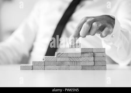 Monochromes Bild des Geschäftsmannes Gebäude ein Graph oder Leiter des Erfolges auf weißer Tisch. Stockfoto