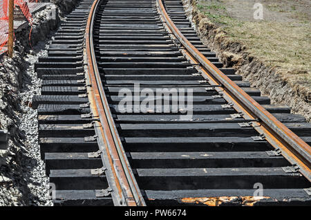 Gekrümmten Gleisen für die S-Bahn Straßenbahn auf Holzschwellen verlegt. Eisenbahn- und Verkehrsinfrastruktur Stockfoto