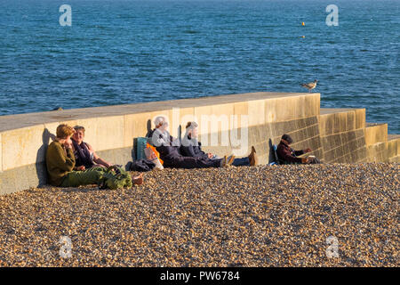 Leute sitzen auf den Strand genießen Sie den späten Abend Sonnenlicht in der Küstenstadt Lyme Regis in Dorset. Stockfoto