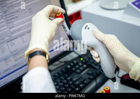 Die Laboratory Assistant hält die Probe in die Hand und trägt die Daten aus der Stichprobe mit einem Strichcode-leser Stockfoto