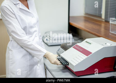 Laboratory Assistant lädt Samples in das Gerät für die Analyse, Seitenansicht Stockfoto