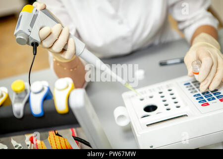 Die Laboratory Assistant stellen eine Blutprobe für die Analyse in einem speziellen Apparat, close-up Stockfoto