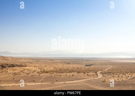 Panorama der Namak Salt Lake, von oben gesehen, mit einer Straße im Vordergrund sichtbar und ein Tal im Hintergrund, am Nachmittag, in Maranjab Stockfoto