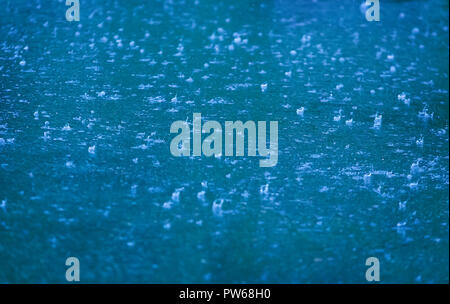 Regen Tropfen fallen im Pool auf Asphalt Stockfoto