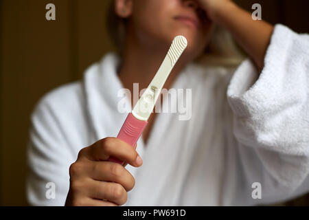 Betroffene Frau im Badezimmer mit Startseite Schwangerschaft Test Stockfoto