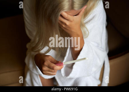 Betroffene Frau im Badezimmer mit Startseite Schwangerschaft Test Stockfoto