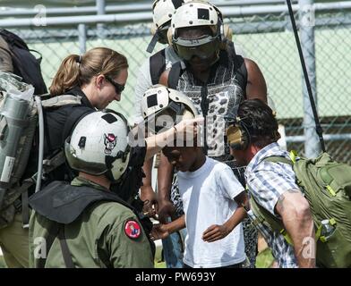 DOMINICA (Sept. 25, 2017) Naval Aircrewman (Hubschrauber) 2. Klasse Nikolaus Glas, zugeordnet zu den Hubschrauber Meer Combat Squadron (HSC) 22, angeschlossen an den amphibischen Angriff Schiff USS Wasp (LL 1), hilft eine Familie für die Evakuierung vorbereiten Nach dem Landfall Hurrikan Maria. Dominica Bewohner werden von ihrer Insel zu den nahe gelegenen Inseln Martinique und Guadalupe evakuiert. Das Verteidigungsministerium ist die Unterstützung der US-Behörde für Internationale Entwicklung (USAID), die Leitung der Föderalen Agentur, dabei helfen, die Betroffenen durch den Hurrikan Maria Leiden zu minimieren und ist eine Komponente Stockfoto