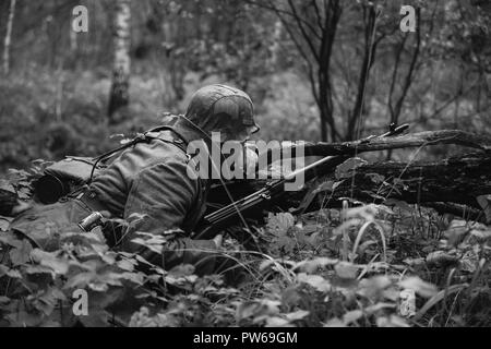 Nicht identifizierte Re-Enactor verkleidet als Soldat der deutschen Wehrmacht Infanterie im zweiten Weltkrieg versteckt sitzen mit Gewehr Waffe In einem Hinterhalt In Graben im Herbst Stockfoto